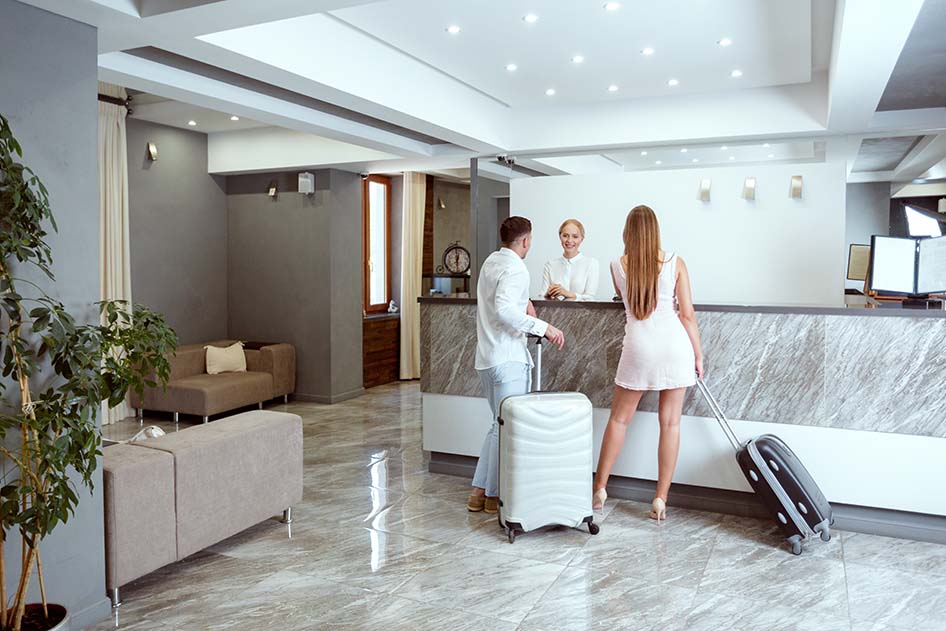 People carrying luggage checking into a modern, sleek hotel