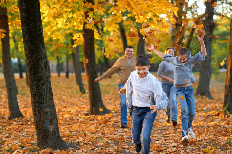 A happy family walks through the woods and plays with the fallen leaves